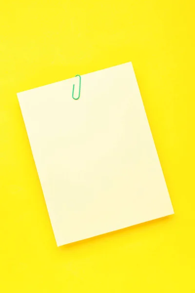 黄色の背景にクリップと紙シート — ストック写真
