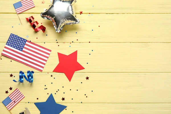 USA flags with stars and serpentine on yellow wooden background. Independence Day celebration