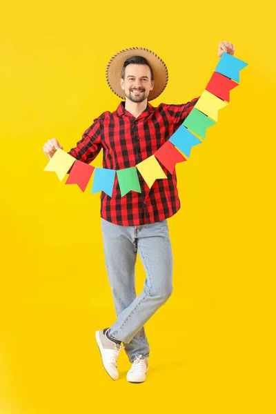 Handsome man with flags on yellow background. Festa Junina (June Festival) celebration