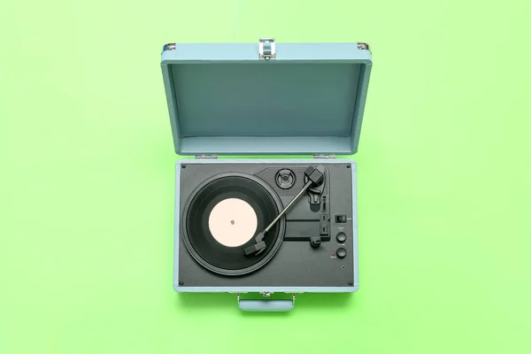 Record player with vinyl disk on green background