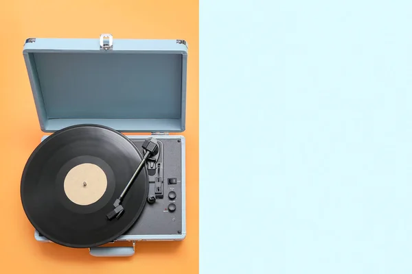 Record player with vinyl disk on color background