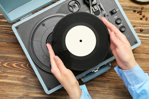 レコードディスクと木製の背景にレコードプレーヤーを持つ女性 クローズアップ — ストック写真