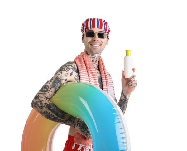 Tattooed man with sunscreen cream and swimming ring on white background