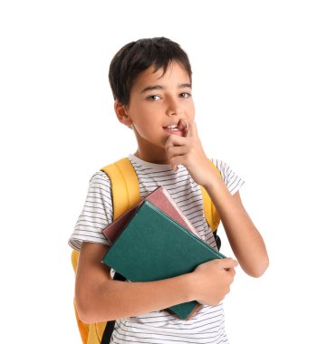 Kitapları beyaz arka planda tırnaklarını yiyen küçük okul çocuğu.