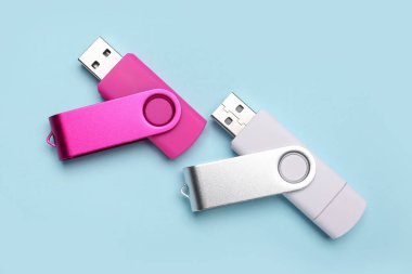 Mavi arkaplanda pembe ve beyaz USB flaş bellekler