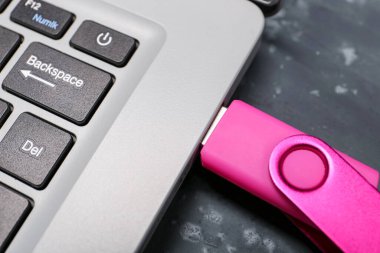 Siyah grunge arka planında pembe USB flash diski olan dizüstü bilgisayar