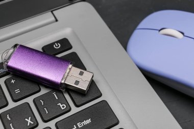 Modern laptop, mor USB flash disk ve siyah grunge arka planda mavi fare