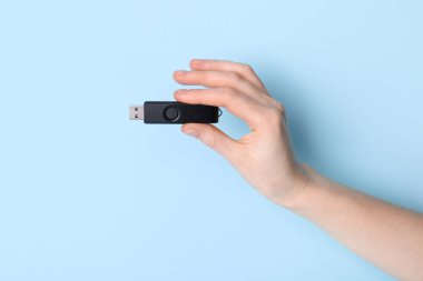 Mavi arkaplanda siyah USB bellek tutan kadın