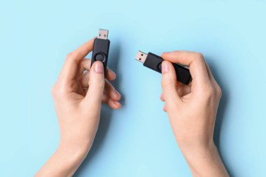 Mavi arkaplanda siyah USB flaş bellek tutan kadın