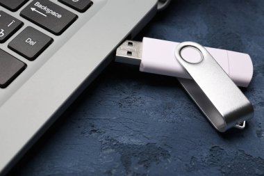 Mavi grunge arka planında beyaz USB flash diski olan modern bir laptop.