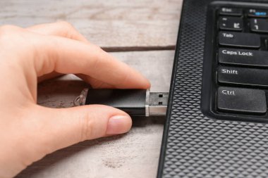 Beyaz tahta arka planda modern dizüstü bilgisayarı olan siyah USB flash disk kullanan bir kadın.