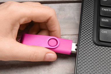 Beyaz tahta arka planda modern dizüstü bilgisayarı olan pembe USB flash disk kullanan bir kadın.
