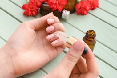 Renkli ahşap arka planda tırnaklarına yağ süren kadın, yakın plan