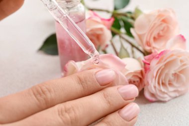 Hafif arka planda tırnak altlarına yağ süren kadın, yakın plan