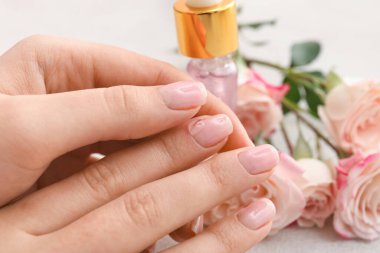 Woman applying oil onto cuticles on light background, closeup clipart