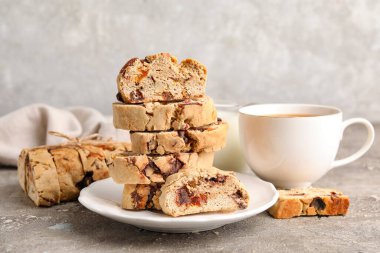Bir tabak dolusu lezzetli bisküvi ve arka planda bir fincan kahve.