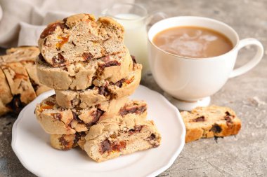 Bir tabak dolusu lezzetli bisküvi ve arka planda bir fincan kahve, yakın plan.