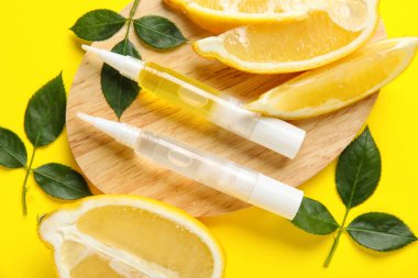 Kütikül yağı kalemli tahta tahta, sarı arka planda limon ve bitki yaprakları, yakın plan