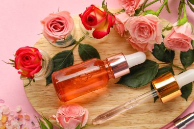 Tahta tahta tahta tahta, tırnak eti yağı şişesi ve pembe arka planda güzel gül çiçekleri, yakın plan.