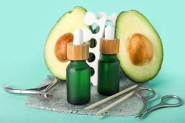 Renk arkaplanında manikür aletleri ve avokado şişeleri ile kompozisyon