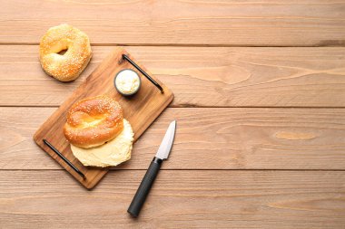 Tahta arka planda susamlı ve krem peynirli lezzetli simitler.