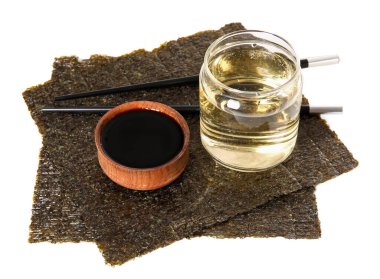 Beyaz arka planda bir bardak pirinç sirkesi, soya sosu ve Norveç çarşafı.