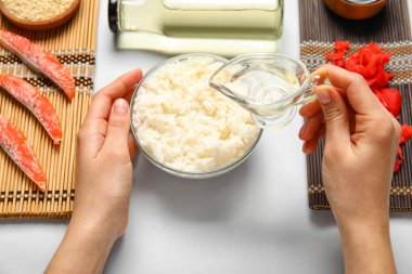 Beyaz arka planda lezzetli suşi ruloları hazırlamak için malzemeli kadın elleri, yakın plan.