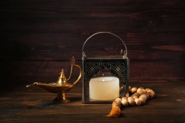 Namaz boncukları ve Aladdin lambasıyla koyu ahşap arka planda Müslüman fener.