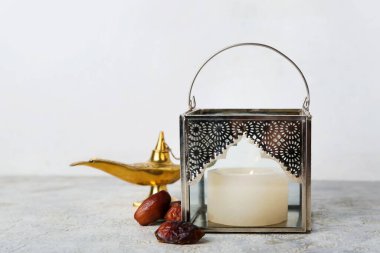 Müslüman lambaları yanan mum ve beyaz duvarın yanındaki masada hurma ağaçları.