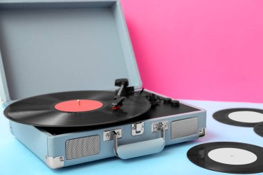 Pembe duvarın yanındaki masada vinil diskleri olan kayıt çalar
