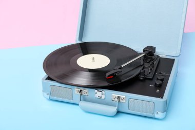 Pembe duvarın yanındaki masada vinil diski olan kayıt çalar