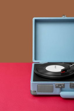 Kahverengi duvarın yanındaki masada vinil diski olan kayıt çalar