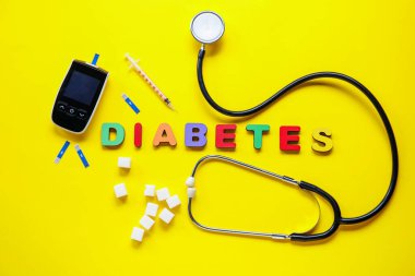 Sarı zemin üzerinde şeker, glukometre ve şırınga ile kelime diabeTES