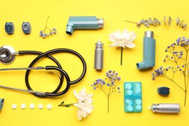 Steteskoplu astım spreyleri, sarı arka planda haplar ve çiçekler.