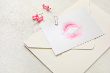 Ruj izi ve beyaz arkaplanda ataç olan zarf, yakın plan