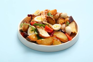 Yumurtalı, domatesli ve açık mavi arka planda pastırmalı lezzetli patates salatası.