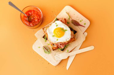 Turuncu arka planda kızarmış yumurta ve pastırmalı lezzetli sandviç.