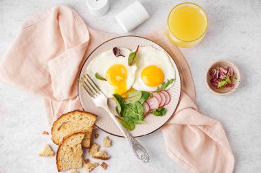 Lezzetli kızarmış yumurta, bir bardak meyve suyu, turp ve açık arkaplanda ıspanak.