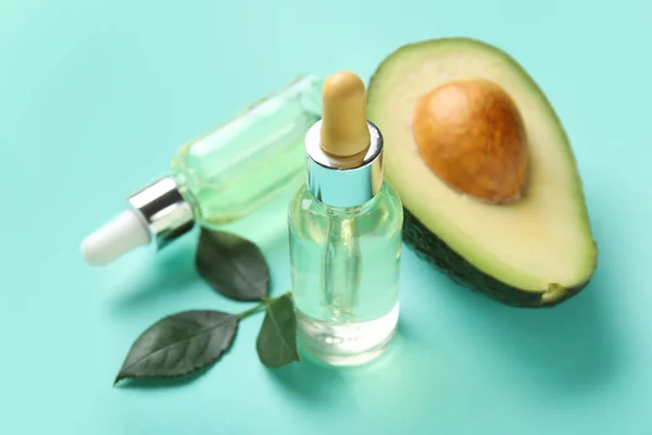 stock image Bottles of cuticle oil and avocado on color background