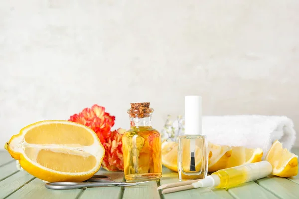 Composition with cuticle oil, manicure instruments and lemon on color wooden table