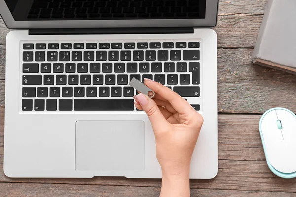 stock image Female hand with USB flash drive, modern laptop and computer mouse on wooden background, closeup