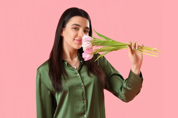 ピンクの背景にチューリップの花の花束と美しい幸せな若い女性 — ストック写真