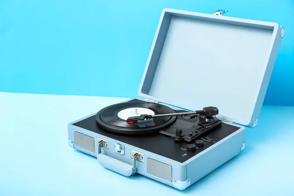 Record player with vinyl disk on blue table