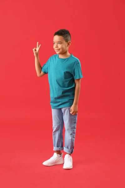 赤の背景に平和のジェスチャーを示す小さなアフリカ系アメリカ人の少年 — ストック写真