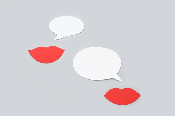 Paper lips with speech bubbles on grey background. Dialogue concept