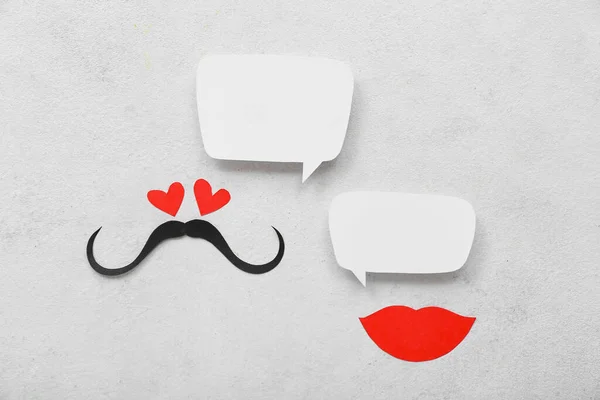 Paper mustache and lips with speech bubbles on white background. Dialogue concept