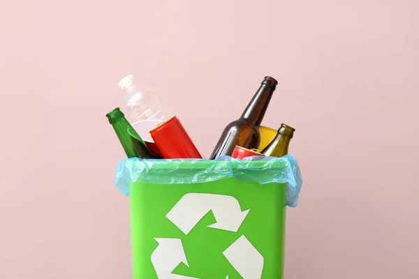 Recycling bin with bottles near pink wall