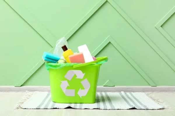 Recycling bin with garbage near green wall