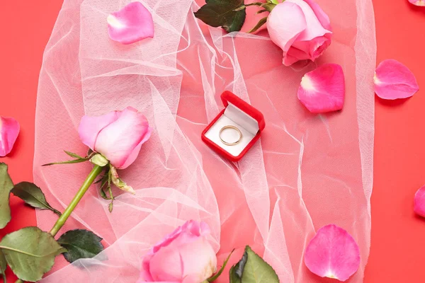 Box with wedding ring, roses and veil on red background