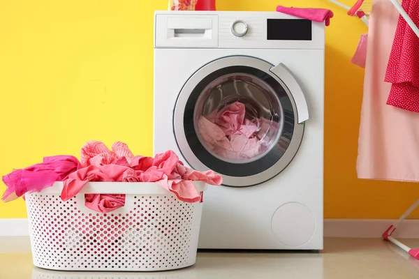 Stock image Basket with dirty clothes and washing machine in laundry room